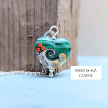 Load image into Gallery viewer, Heart-shaped pendant with beachy designs on a wooden surface, branded 'Sand &amp; Sea Classic'.