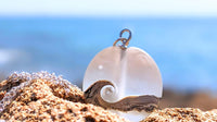 Frosted glass pendant with wave on a stony beach with blurred blue sea in the background